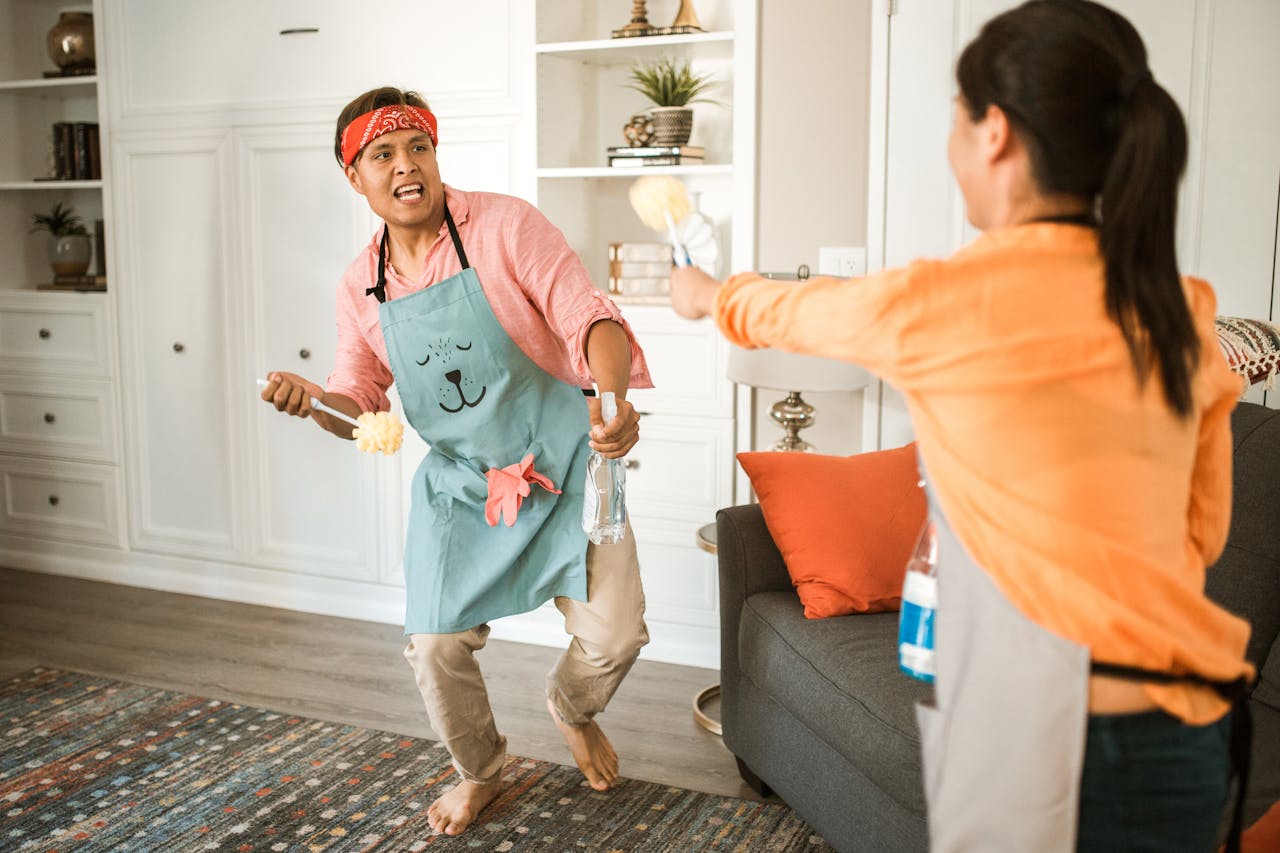 Two adults engaged in playful cleaning, showcasing a lively home atmosphere.